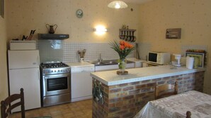 Une cuisine compacte équipée d’une cuisinière, d’un four, d’un four à micro-ondes et d’un petit coin repas avec une table.
