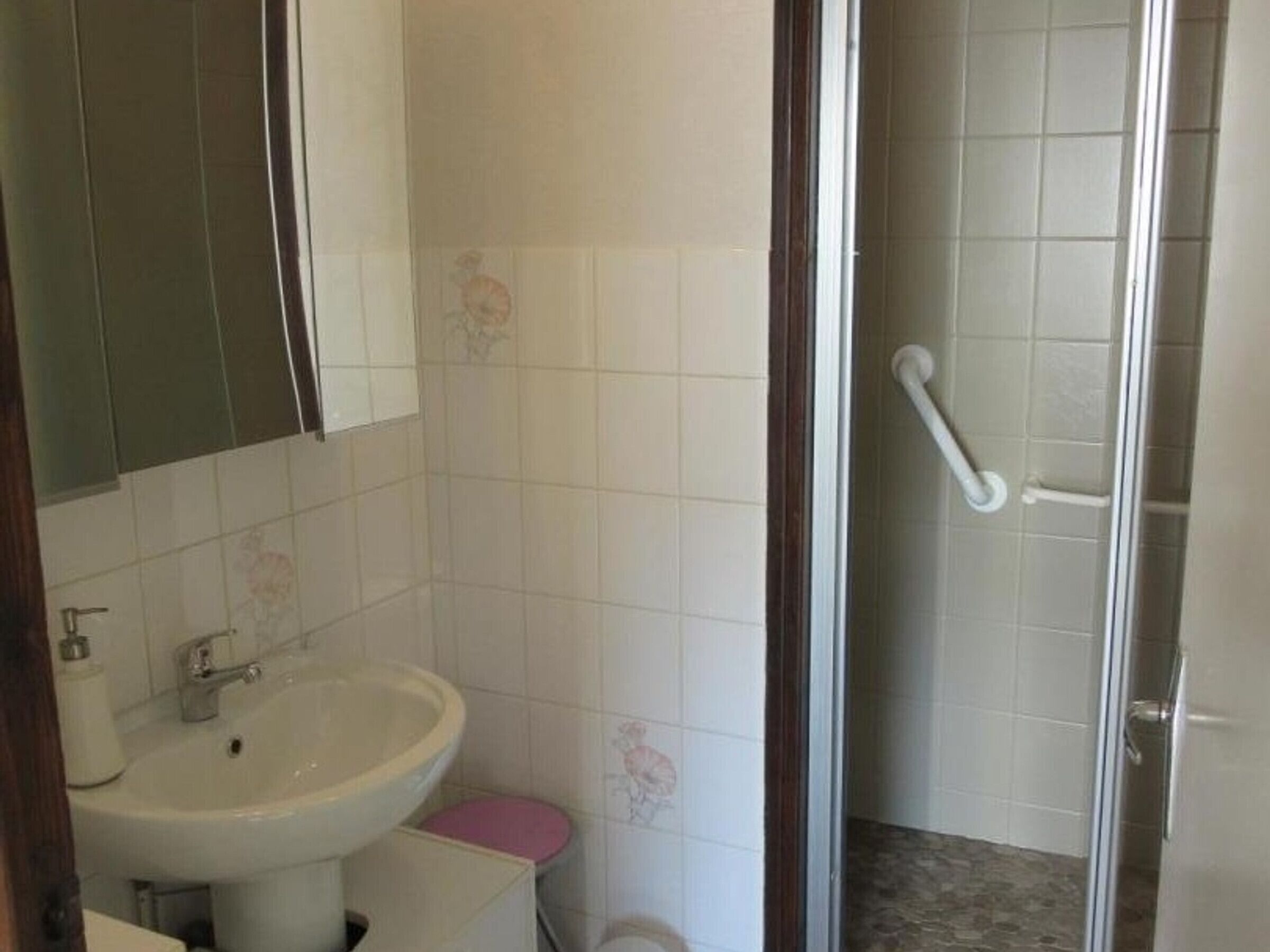 A bathroom with a sink, toilet, and shower area.