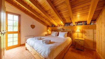Een slaapkamer met houten frame, een bed, nachtkastjes, een raam en een hartvormige decoratie aan de muur.