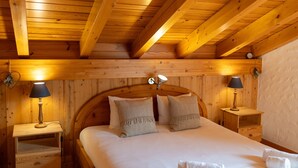 A wooden cabin bedroom with a bed, two bedside tables with lamps, and a wooden ceiling. - Chalet Pierre Blanche - Ski-in/out (Haute-Nendaz)