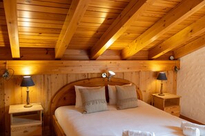 A wooden cabin bedroom with a bed, two bedside tables with lamps, and a wooden ceiling. - Chalet Pierre Blanche - Ski-in/out (Haute-Nendaz)