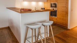 A compact kitchen with a wooden countertop, two white bar stools, and built-in appliances. - Olympic R2 - ski lift Nendaz (Haute-Nendaz)