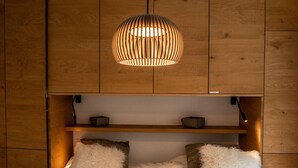 A bed with a fluffy white blanket, a wooden headboard, and a hanging light fixture. - Olympic R2 - ski lift Nendaz (Haute-Nendaz)