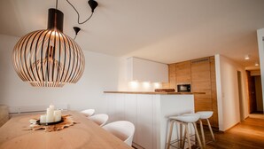 A modern kitchen with a wooden island, white bar stools, and a dining table with candles. - Olympic R2 - ski lift Nendaz (Haute-Nendaz)