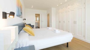 A modern hotel room with a large bed, a desk, and a wardrobe. - Treasure | The Rentals Collection (San Sebastián)
