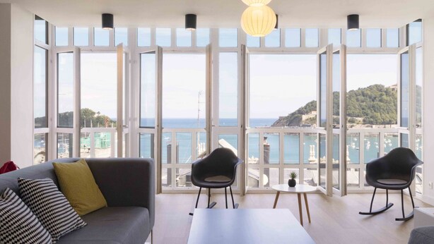 A modern living room with a large window overlooking a scenic coastal view. - Treasure | The Rentals Collection (San Sebastián)