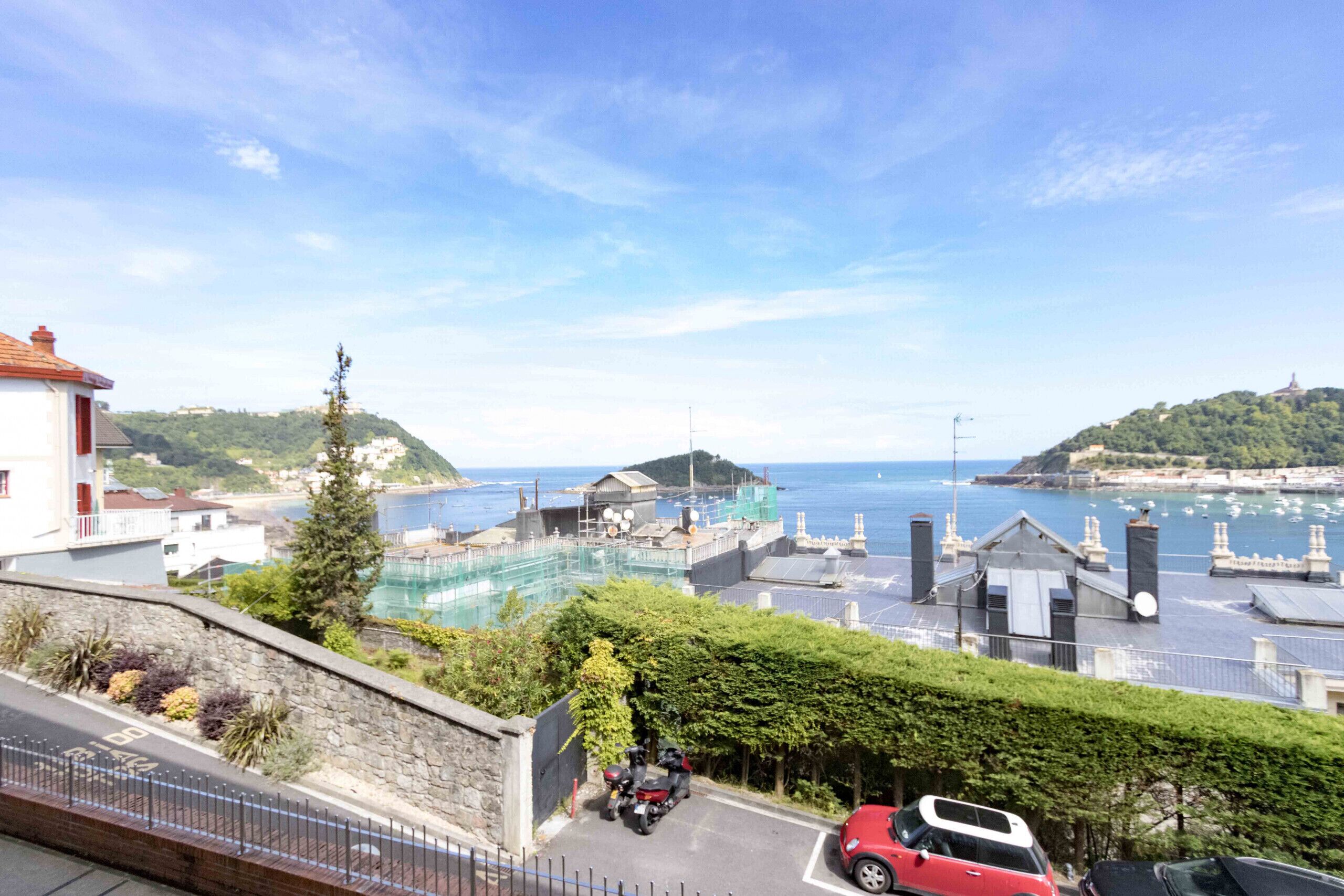 A coastal view with a marina, buildings, and a clear sky.