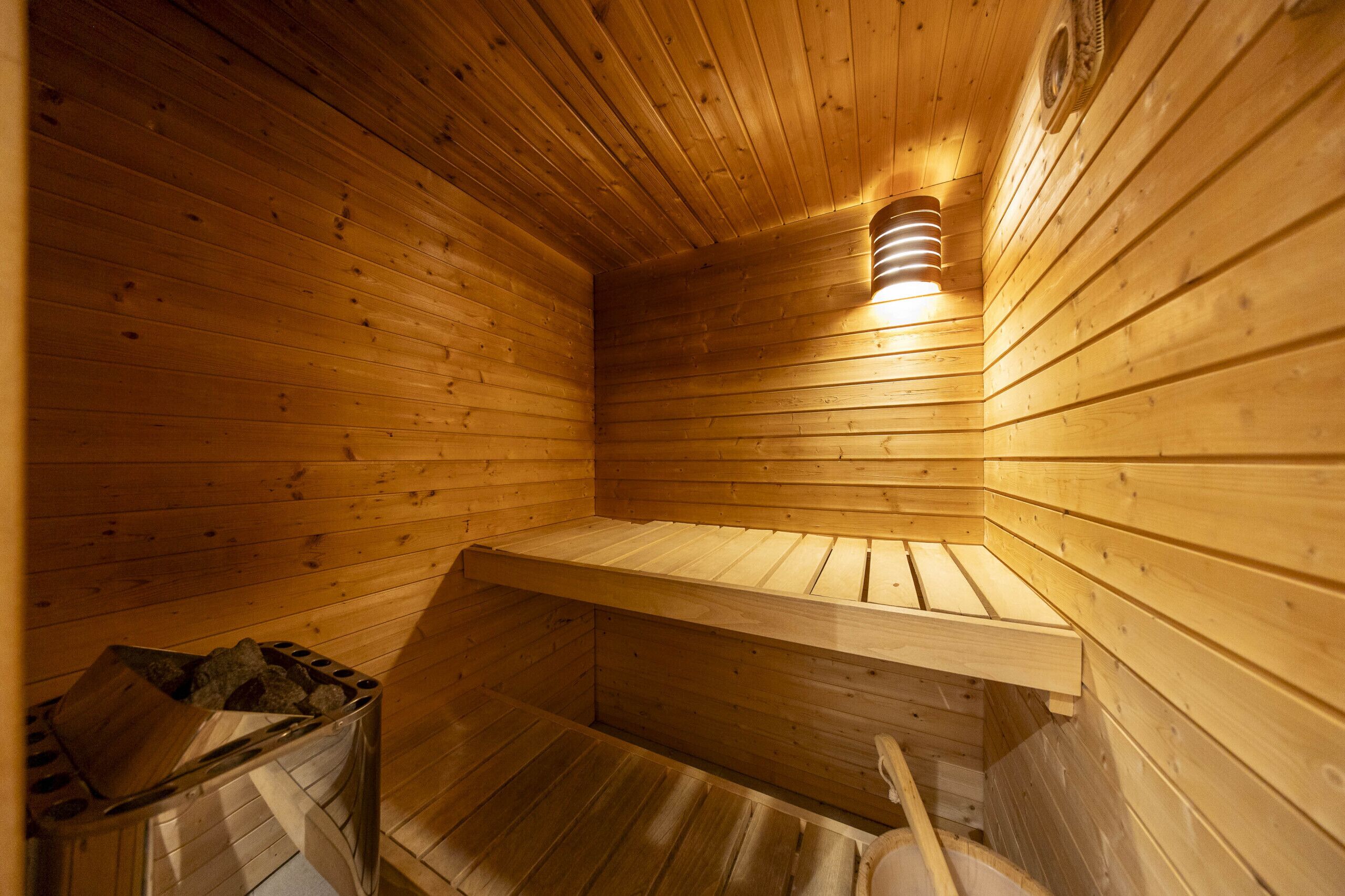 Una sauna in legno con tetto spiovente, una panca e un fiorale a parete.