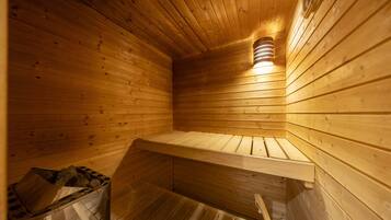Una sauna in legno con tetto spiovente, una panca e un fiorale a parete.