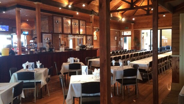 Ein Restaurant mit Holzvertäfelung, gedeckten Tischen und einer Bar.