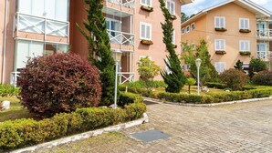 Un edificio de varios pisos con balcones, un patio empedrado y jardines bien cuidados.