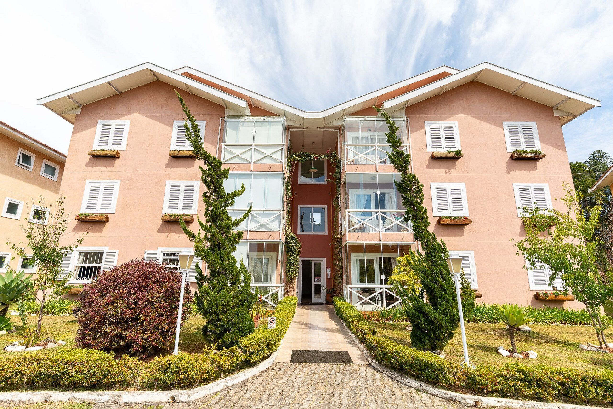 A multi-story building with a central entrance, surrounded by well-maintained gardens and a paved pathway leading to the entrance.