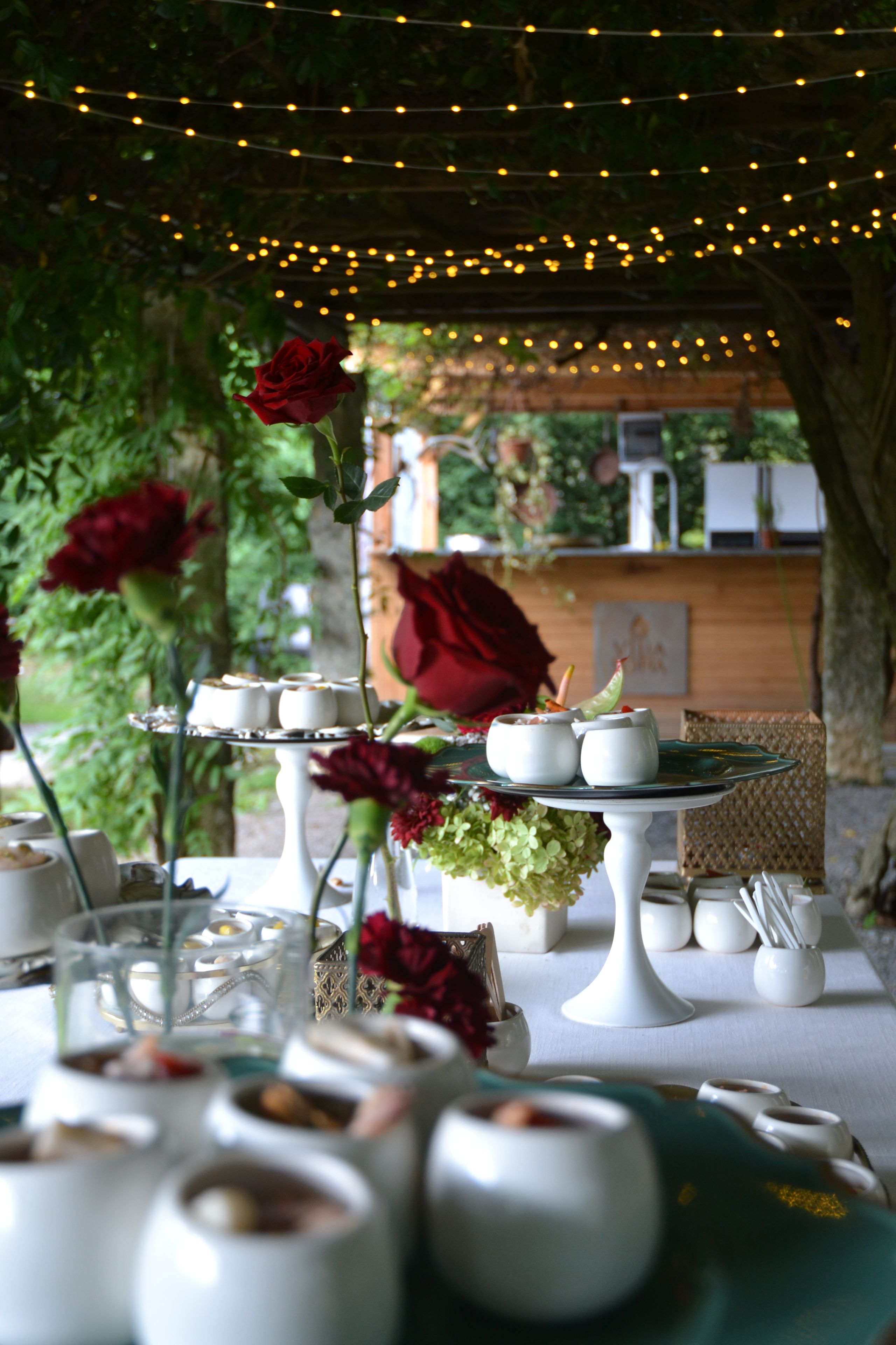 Une table mise pour un repas, avec de la vaisselle blanche et un bouquet de roses en guise de décoration centrale.