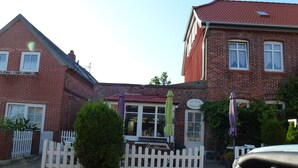 A brick building with a cafe named "Die Kleine KaffeeStube" and a white picket fence in front.