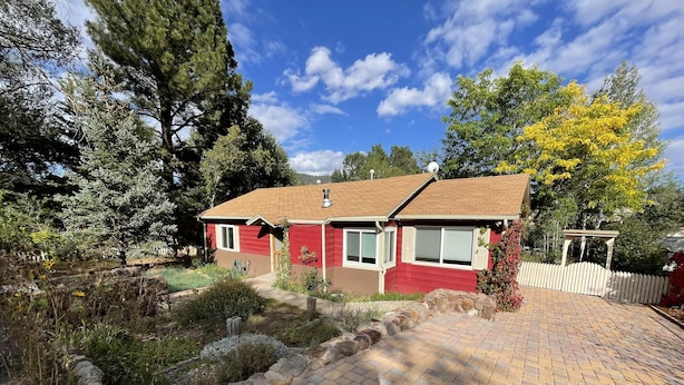 A single-story house with a brick driveway, surrounded by a stone wall and various plants. - Cottage in Flagstaff's NoHo (Flagstaff)
