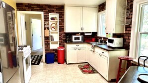 A compact kitchen with white cabinets, a refrigerator, a microwave, and a sink. - Cottage in Flagstaff's NoHo (Flagstaff)
