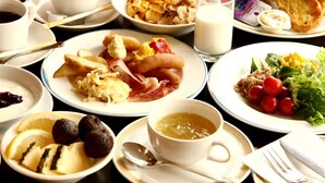 Una abundante mesa de desayuno con varios platos, incluyendo huevos, tocino, tostadas y una ensalada.