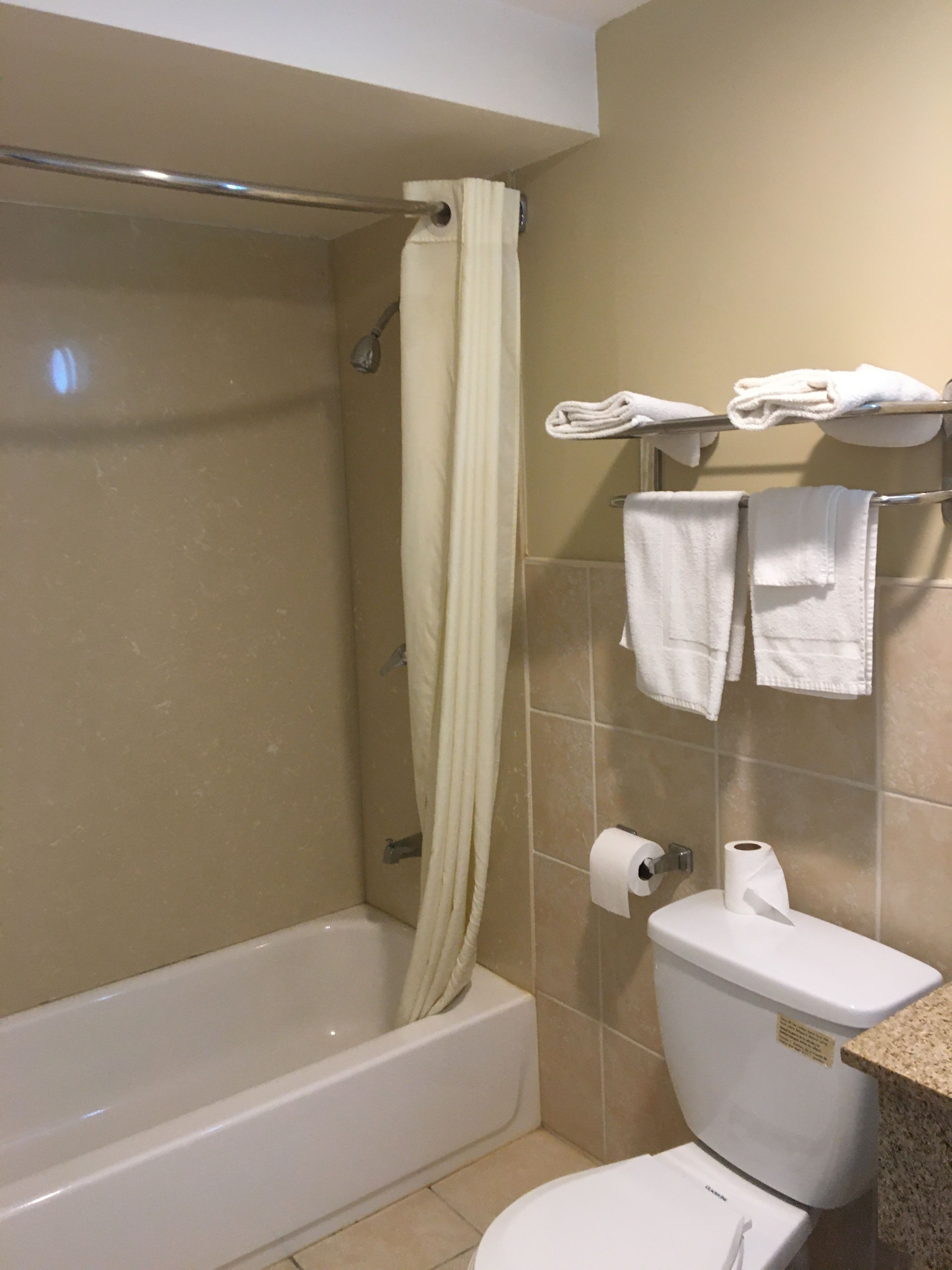 A bathroom with a bathtub, toilet, and towel rack.