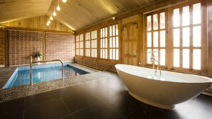 Ein Spa-Bereich mit einer großen Badewanne, einem kleinen Pool und Holzwänden.