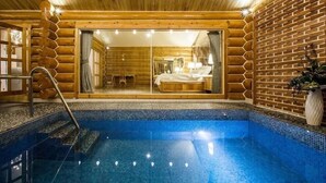 Ein Blockhaus mit Schwimmbad, Holzwänden und einem sichtbaren Schlafzimmer mit Bett und Fenster.