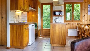 Una cocina de madera con lavavajillas integrado, microondas y ventana con vistas a la vegetación.
