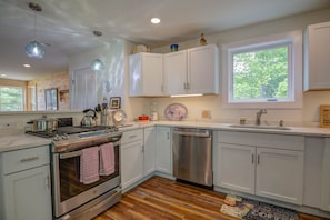 A modern kitchen with white cabinets, stainless steel appliances, and a wooden floor. - LOVELY, LUXURY, NEW BIG SEBAGO HOUSE, WATER ACCESS,
INCLUDES DOCK & MOORING (Standish)