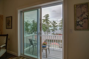 Enjoy the serene view from your deck, featuring a comfortable chair and a small table with a potted plant.