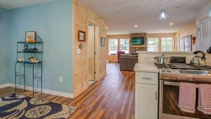 A spacious kitchen with a stone fireplace, wooden cabinets, and a modern stove. - LOVELY, LUXURY, NEW BIG SEBAGO HOUSE, WATER ACCESS,
INCLUDES DOCK & MOORING  (Standish)