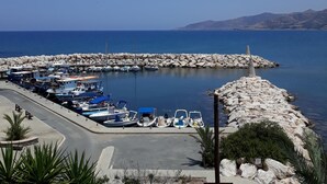 Un port de plaisance avec des bateaux amarrés, une digue rocheuse et un ciel bleu dégagé.