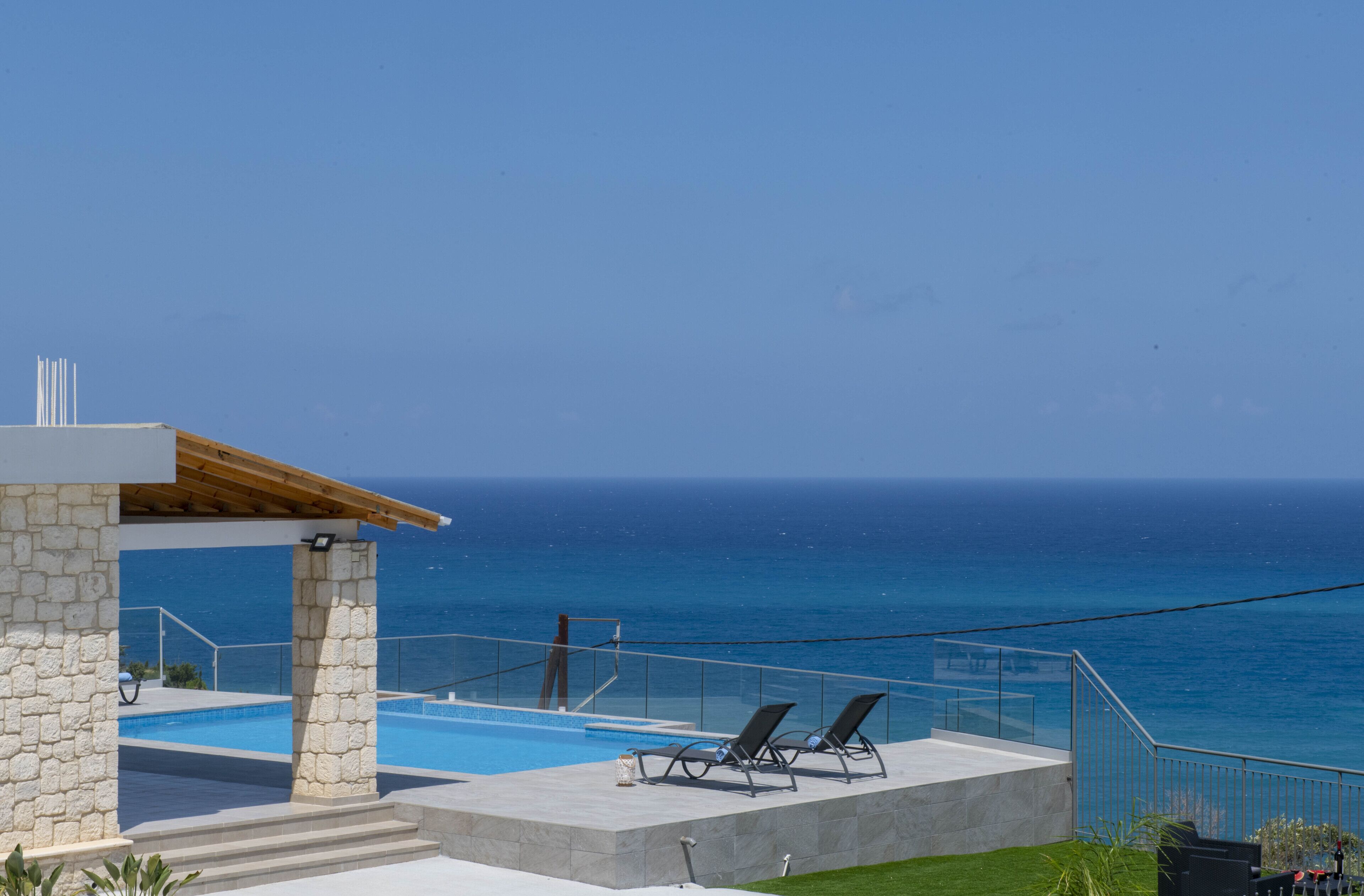 A pool area with two lounge chairs and a stone structure.