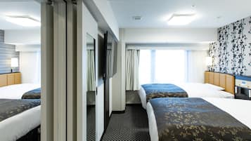 Ein Hotelzimmer mit zwei Betten, einem Flachbildfernseher, einer Minibar und einem großen Fenster mit Vorhängen.