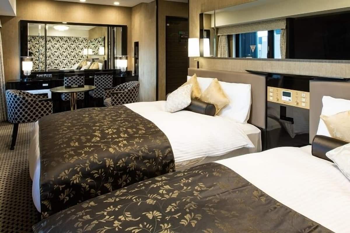 A hotel room with two beds, a desk, and a seating area.