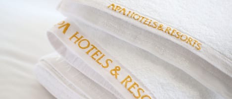 A stack of white towels with embroidered text reading "AAA HOTELS & RESORTS".
