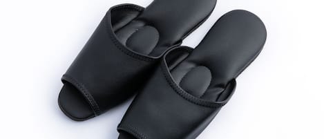 Un par de zapatos negros de vestir sin cordones, con suela texturizada y una tira en la parte superior.