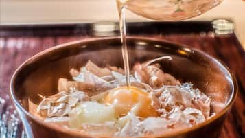 A bowl with shredded meat and a raw egg being poured into it.