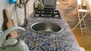 A kitchen with a patterned backsplash, a gas stove, a sink, and a kettle. - "Il Sipario": The Elegance and Comfort of Palazzo Accolla (Siracusa)