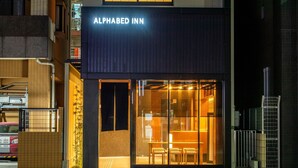 L’extérieur de l’hôtel Alphabed Inn se distingue par sa façade moderne, un panneau lumineux bien visible, de grandes fenêtres en verre et une entrée facilement identifiable.