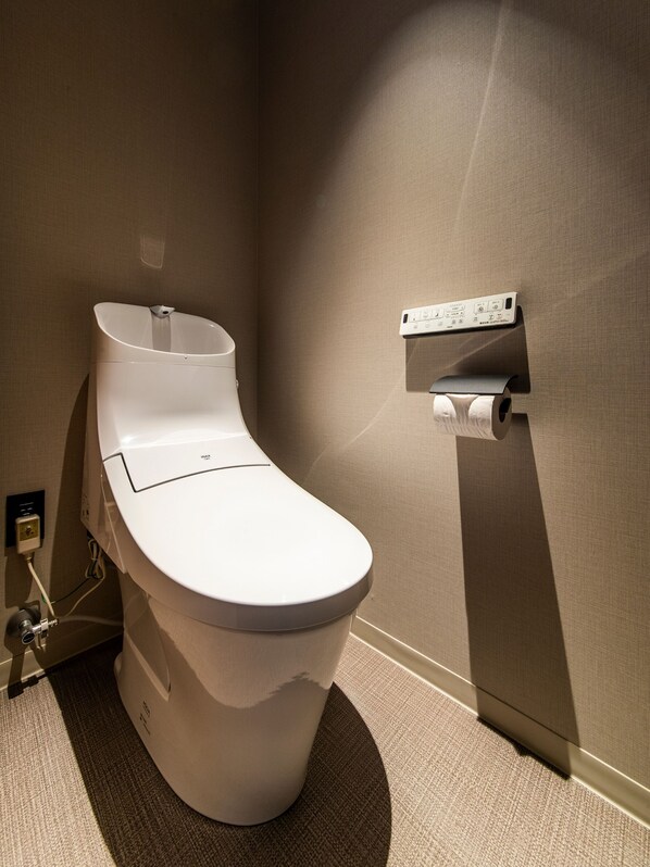 A modern toilet with a wall-mounted bidet and a paper towel dispenser. - ALPHABED INN Fukuoka Ohori Park (Fukuoka)