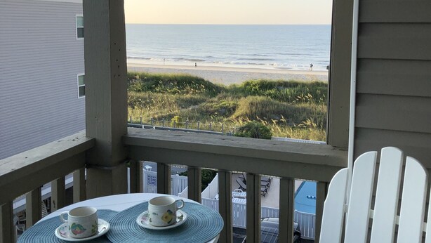 A balcony with a table set for two, overlooking a beach. - North Myrtle Beach Vacation Get Away (North Myrtle Beach)