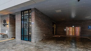 A modern hotel lobby with a reception desk, a glass elevator, and a parking sign. - Brown Dot Hotel Deokcheon (Busan)
