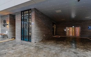 A modern hotel lobby with a reception desk, a glass elevator, and a parking sign. - Brown Dot Hotel Deokcheon (Busan)