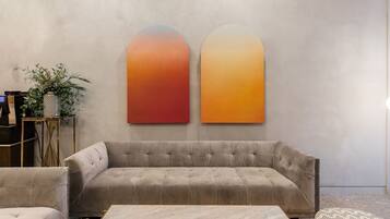 Uma sala de estar moderna com um sofá cinzento, uma mesa de centro e duas obras de arte abstratas nas paredes.
