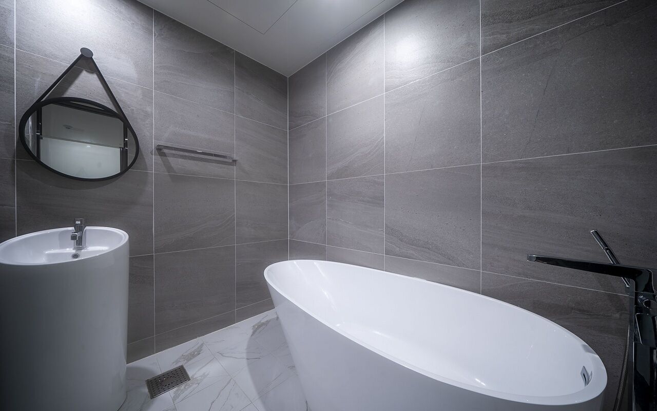 A modern bathroom with a freestanding bathtub, a wall-mounted sink, and a mirror.