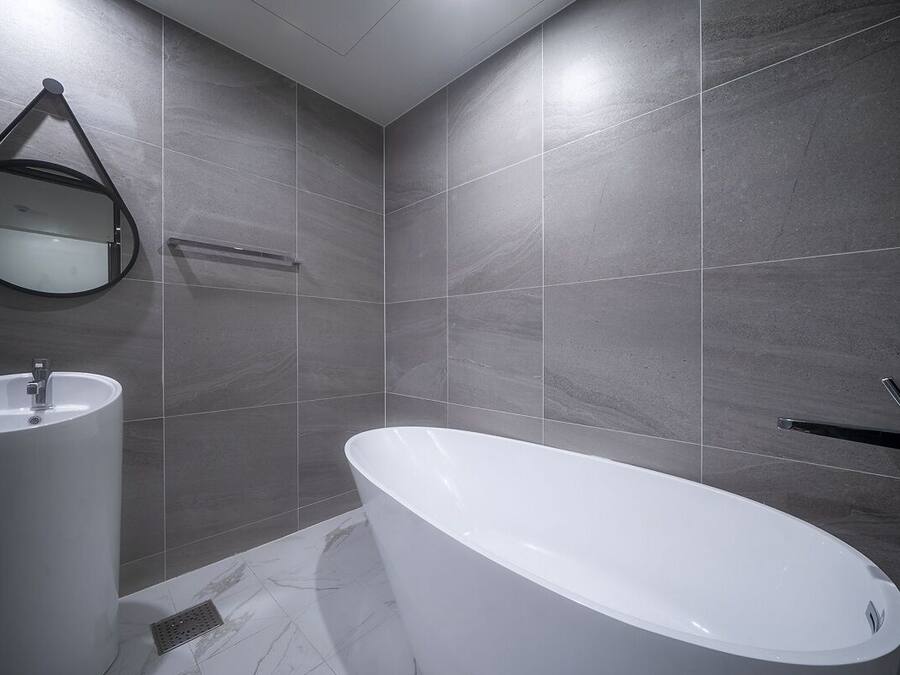 Un baño moderno con una bañera independiente, un lavamanos montado en la pared y un espejo.