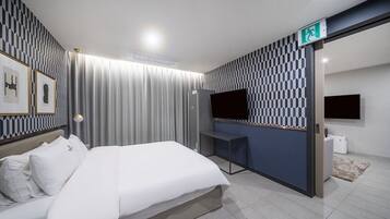 Quarto de hotel moderno com cama, escrivaninha, TV de tela plana e parede estampada.
