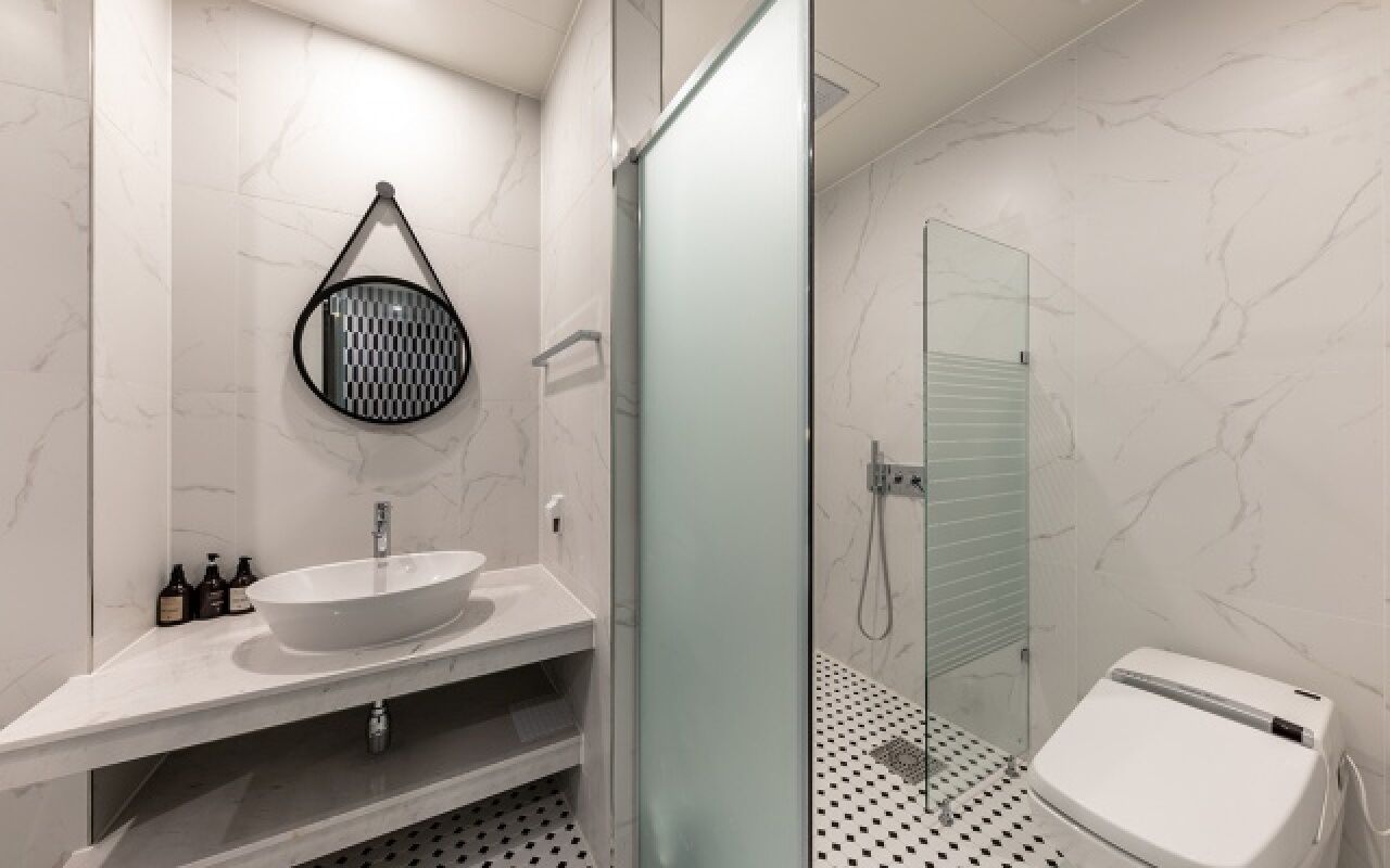 A modern bathroom with a large white sink, a glass shower enclosure, and a toilet.