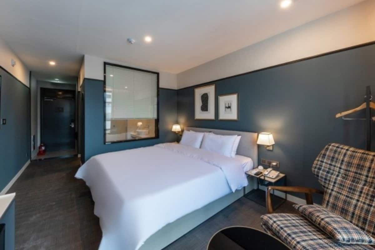 A hotel room with a large bed, bedside tables, a chair, and a TV.