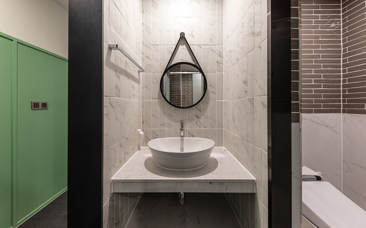 A bathroom with a round sink, a mirror, and a green door.
