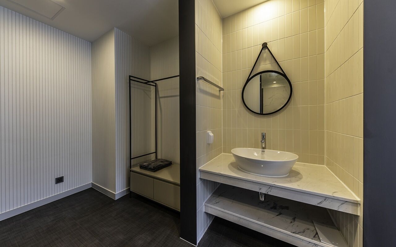 Une salle de bain moderne avec un lavabo blanc, un miroir et une cabine de douche.