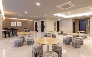 A modern hotel lobby with round tables, patterned ottomans, and a clean, minimalist design. - Brown Dot Hotel Deokcheon (Busan)